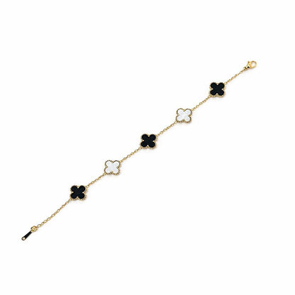 Gold bracelet with black and white clover-shaped charms on a white background