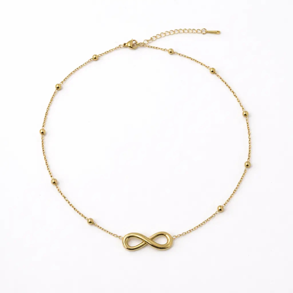 Gold infinity necklace on a white background