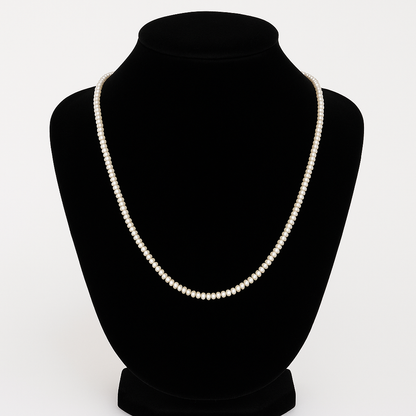 Pearl necklace on a black mannequin bust against a white background

