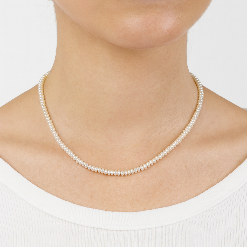 Pearl necklace worn by a person on a plain background

