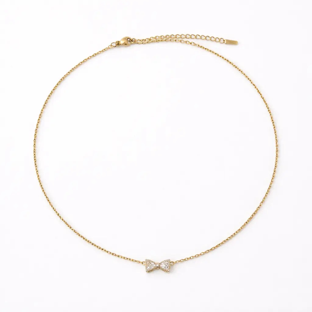 Gold necklace with a bow-shaped pendant on a white background
