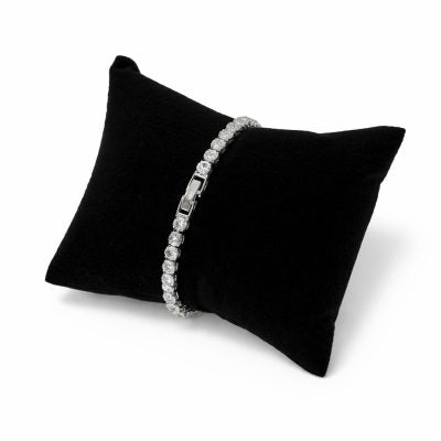 Silver bracelet on a black cushion against a white background

