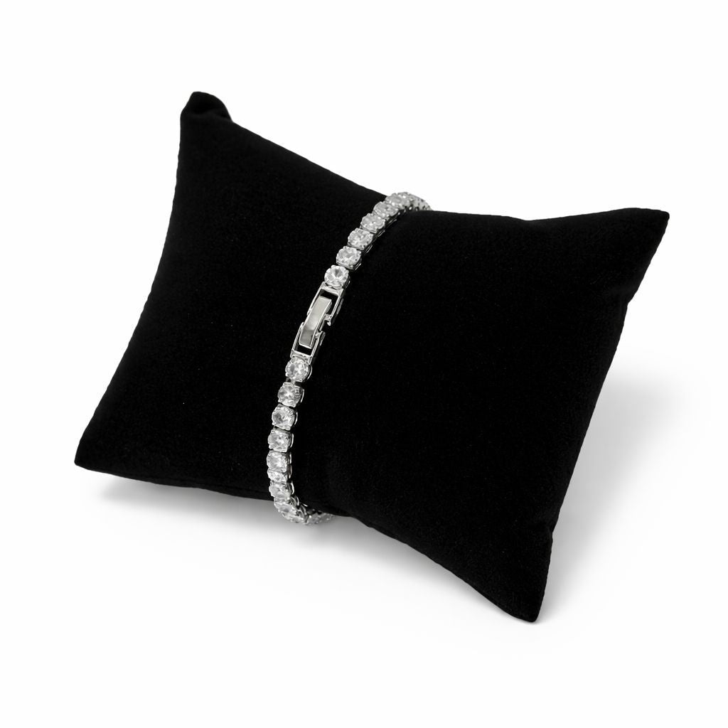 Silver bracelet on a black pillow against a white background

