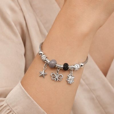 Silver bracelet with various charms on a wrist against a neutral background
