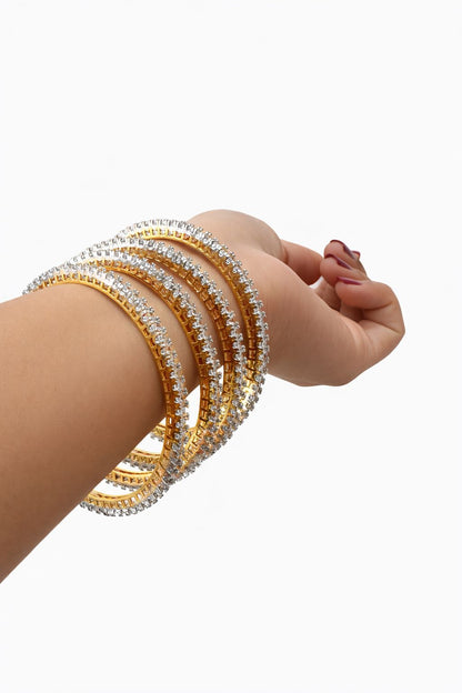 Gold and silver bangles on a person's wrist against a white background
