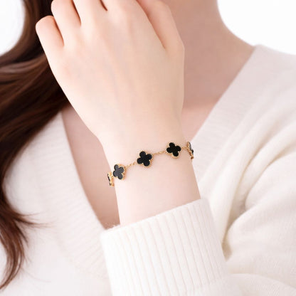 Bracelet with black flower charms on a wrist, wearing a white sweater.