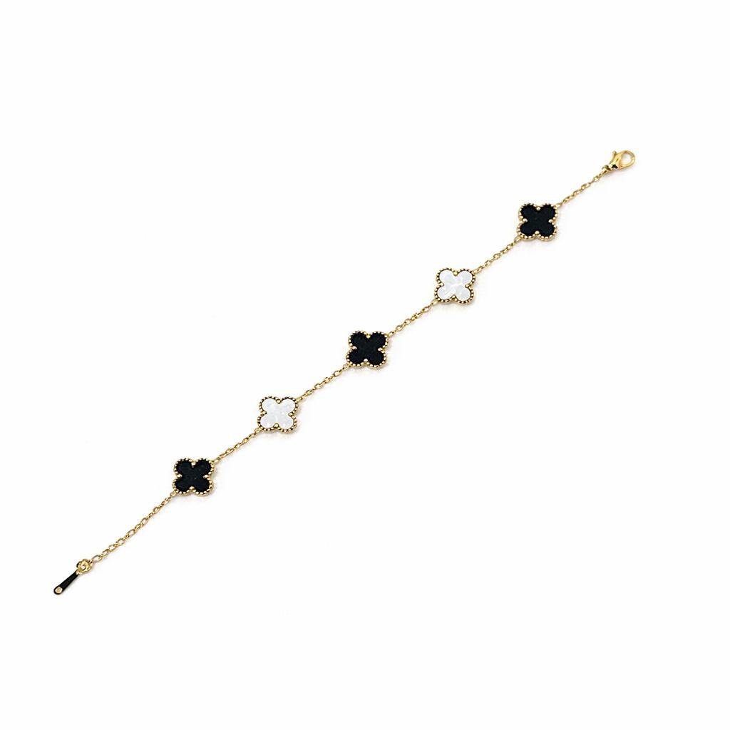 Gold bracelet with black and white clover-shaped charms on a white background