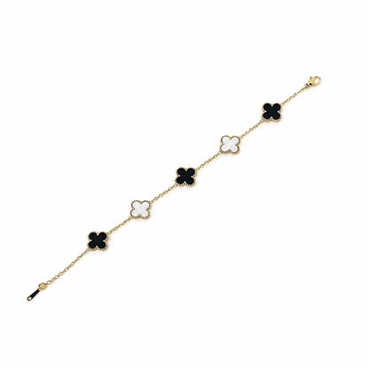 Gold bracelet with black and white clover-shaped charms on a white background