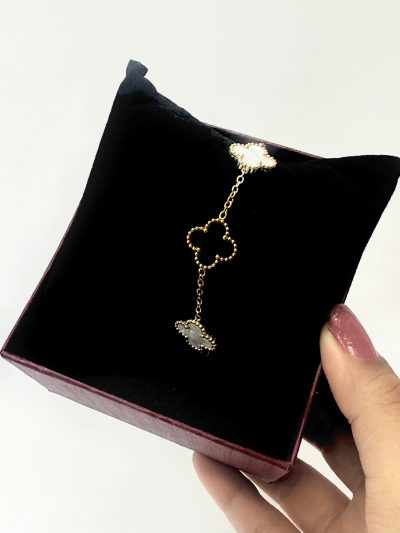 Gold heart-shaped earring on a black cushion with a hand holding the box.