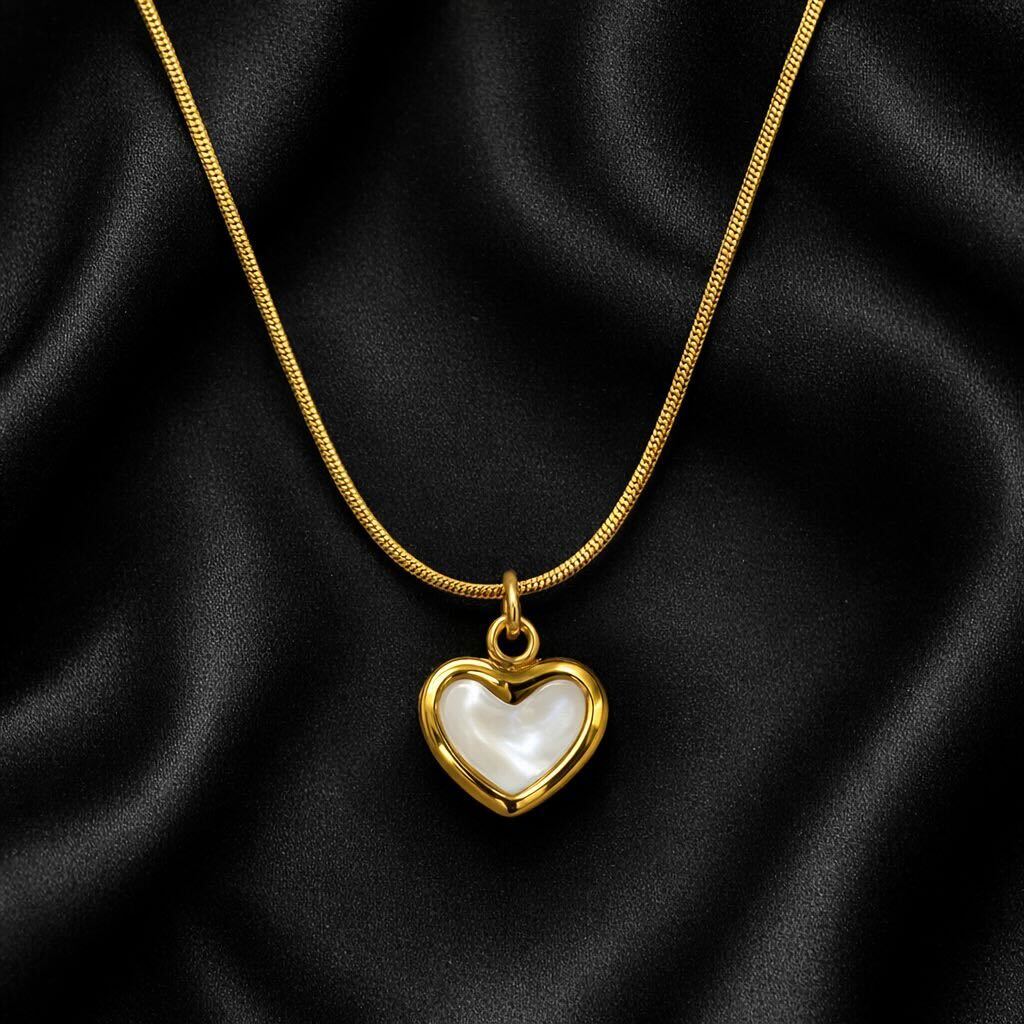 Gold necklace with a heart-shaped pendant on black fabric