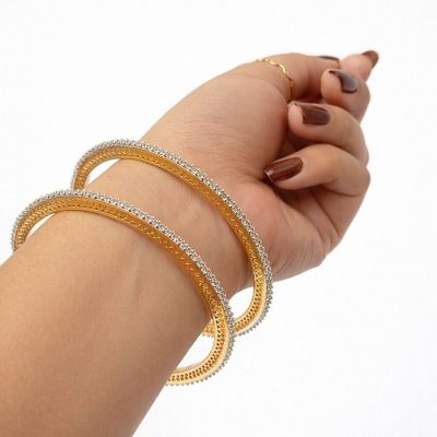 Hand wearing two gold bracelets on a white background