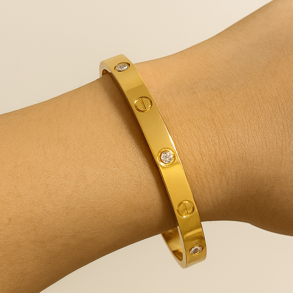Gold bracelet on a hand with a plain background