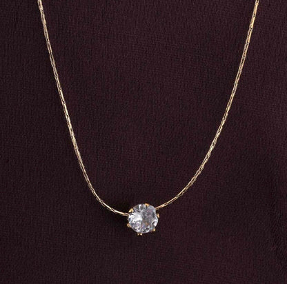 Gold necklace with a diamond pendant on a dark background
