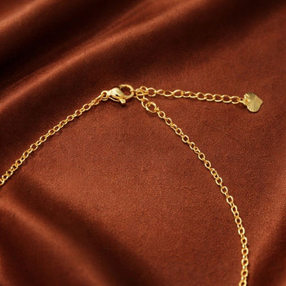 Gold chain bracelet on a brown satin background